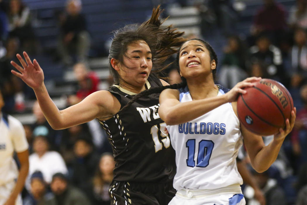 Centennial’s Ajanhai Phoumiphat (10) goes to the basket against West’s Rachel Arakawa (15) while drawing a foul during a basketball game at Centennial High School in Las Vegas on Sat ...