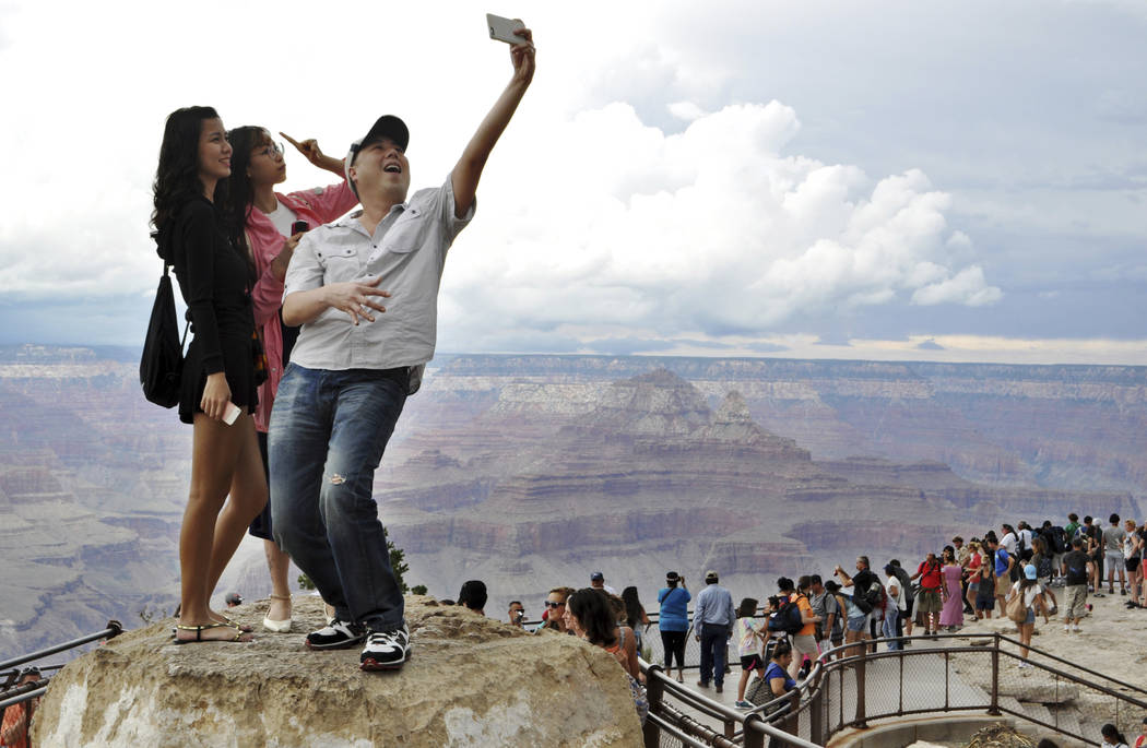 In this Aug. 2, 2015, file photo, tourists Joseph Lin, Ning Chao, center, and Linda Wang, left, pose for a selfie along the south rim at Grand Canyon National Park, Ariz. The Grand Canyon is celeb ...