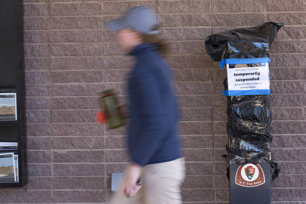 A visitor walks past a temporarily suspended pay station affected by the partial government shutdown at the Furnace Creek Visitor Center at Death Valley National Park in Calif., on Friday, Jan. 4, ...