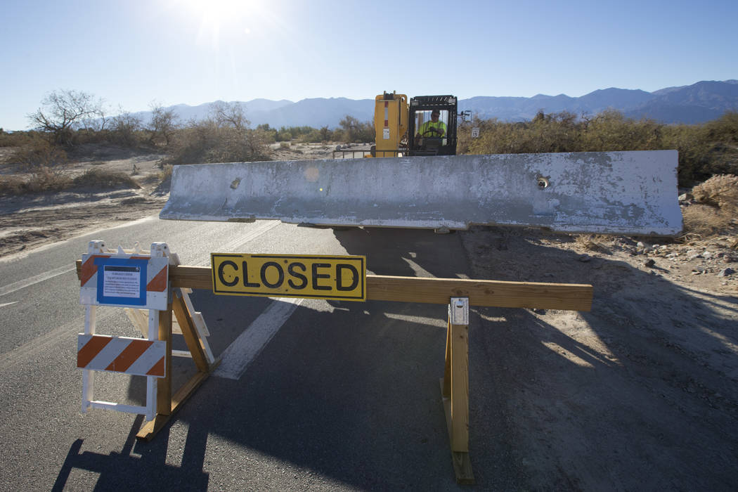 A maintenance worker with the National Park Service sets a jersey barrier to block the entrance to the Furnace Creek Campground after it was closed following health and safety concerns due to lack ...