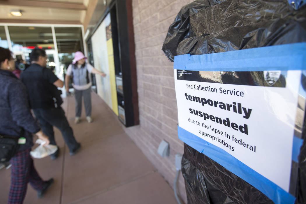 Visitors look over a map of Death Valley National Park near a temporarily suspended pay station affected by the partial government shutdown at the Furnace Creek Visitor Center at Death Valley Nati ...