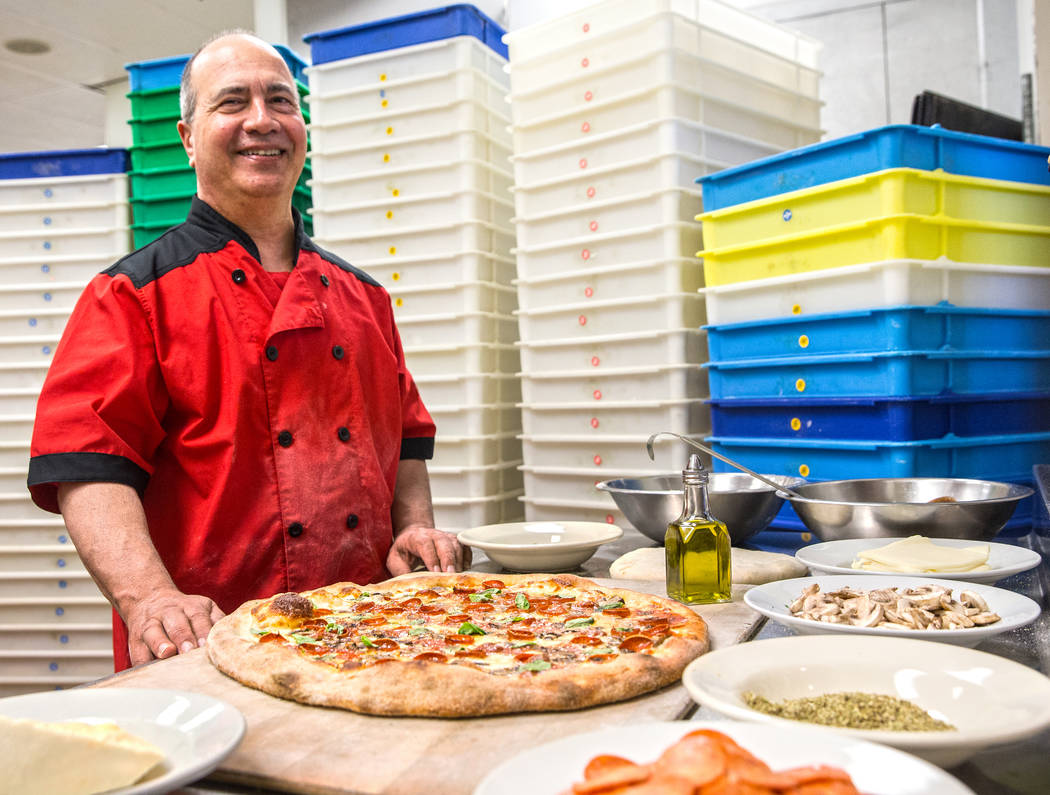 Chef/co-owner John Arena adds fresh basil to an Olde New York specialty pizza, with dozens of treys of pizza dough prepared in advance for the Super Bowl LI rush covering the wall behind him, on T ...