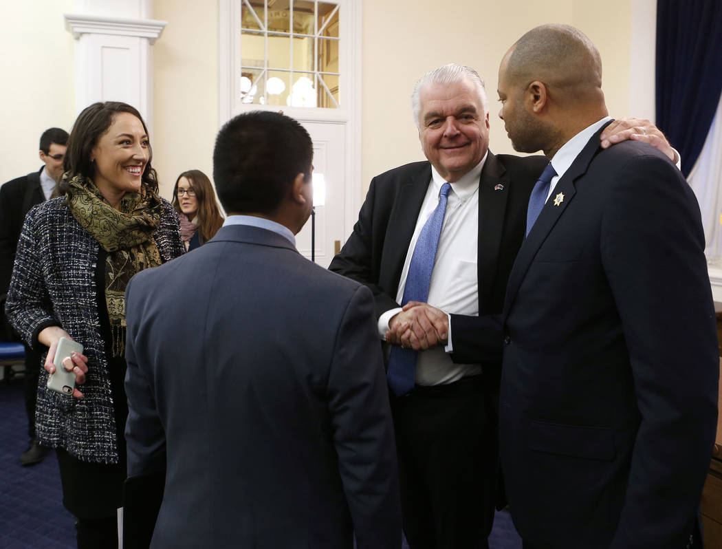 Nevada Gov. Steve Sisolak, center, shakes hands after with Attorney General Aaron Ford after signing his first executive order calling for a task force to address sexual harassment at the Capitol, ...