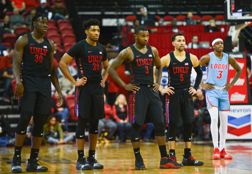 UNLV Rebels forward Jonathan Tchamwa Tchatchoua (30), forward Nick Blair (20), guard Amauri Hardy (3), guard Noah Robotham (5) and New Mexico Lobos guard Keith McGee (3) watch free throws from hal ...