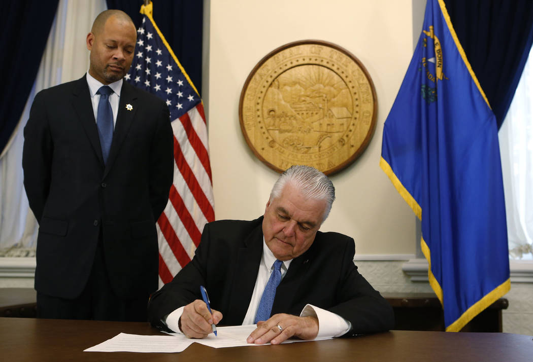 With newly sworn Attorney General Aaron Ford at his side, Nevada Gov. Steve Sisolak signs his first executive order calling for a task force to address sexual harassment at the Capitol, in Carson ...