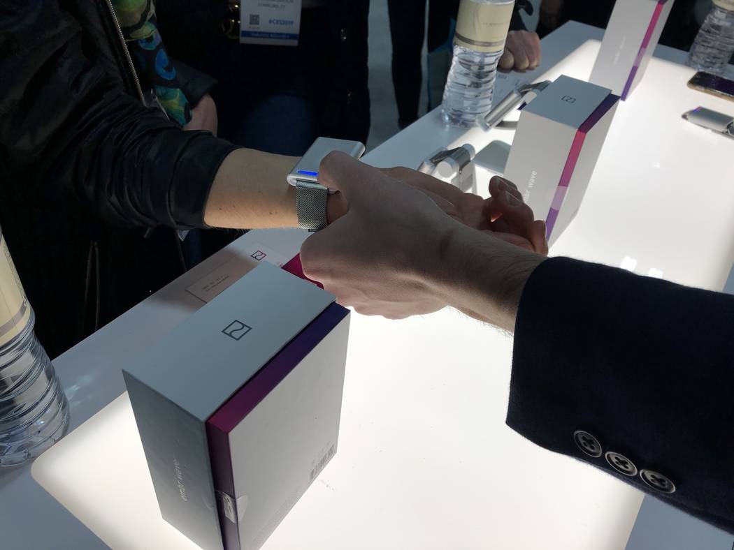 Embr Labs vice president of marketing Jake Abrams fits a CES 2019 attendee with an Embr Wave bracelet. The device makes the wearer feel five degrees warmer or cooler and sells in the U.S. and Cana ...