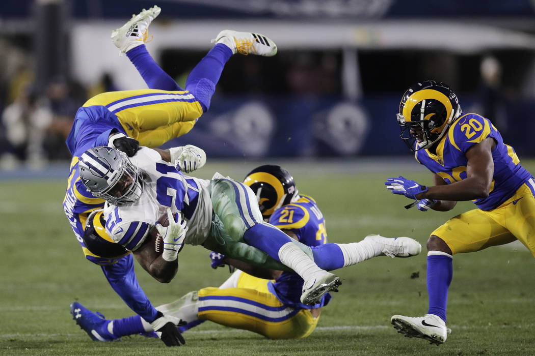 Dallas Cowboys running back Ezekiel Elliott is tackled by Los Angeles Rams linebacker Dante Fowler, top, and cornerback Aqib Talib during the second half in an NFL divisional football playoff game ...