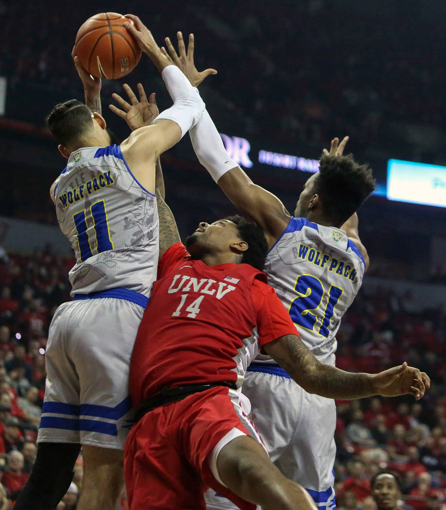 Nevada Wolf Pack forward Cody Martin (11) gains possession of the ball while Nevada Wolf Pack guard Lindsey Drew (14) and Nevada Wolf Pack forward Jordan Brown (21) reach for the ball during the f ...