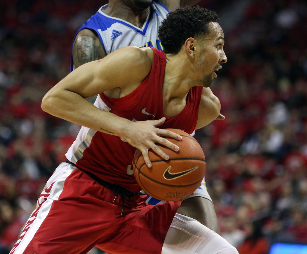 UNLV Rebels guard Noah Robotham (5) protects the ball while under pressure from Nevada Wolf Pack forward Jordan Caroline (24) during the second half of a basketball game at the Thomas & Mack C ...