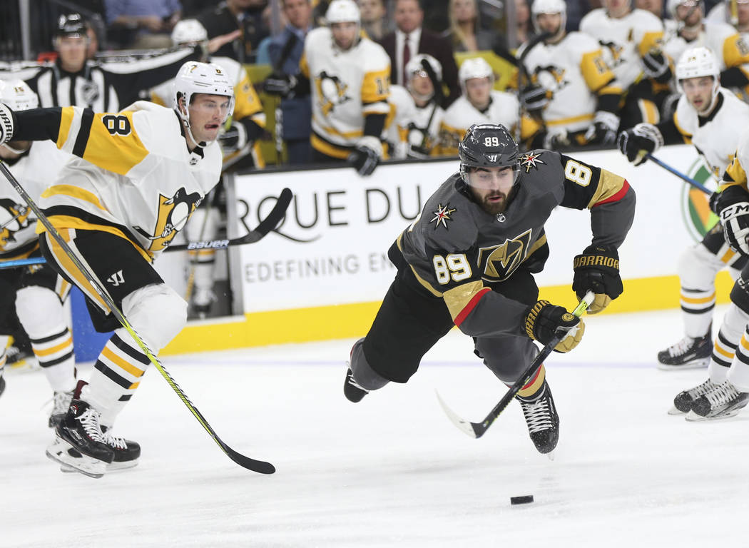 Golden Knights right wing Alex Tuch (89) slips while moving the puck past Pittsburgh Penguins defenseman Brian Dumoulin (8) during the first period of an NHL hockey game at T-Mobile Arena in Las V ...