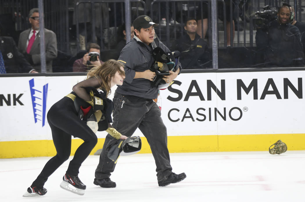 Members of the Golden Knights ice crew pick up hats on the ice that were thrown in celebration of a hat trick by Jonathan Marchessault, not pictured, during the third period of an NHL hockey game ...