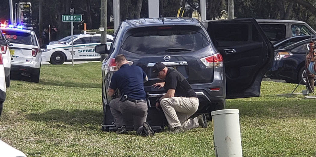 Law enforcement officials take cover outside a SunTrust Bank branch, Wednesday, Jan. 23, 2019, in Sebring, Fla. Authorities say they've arrested a man who fired shots inside the Florida bank. (The ...