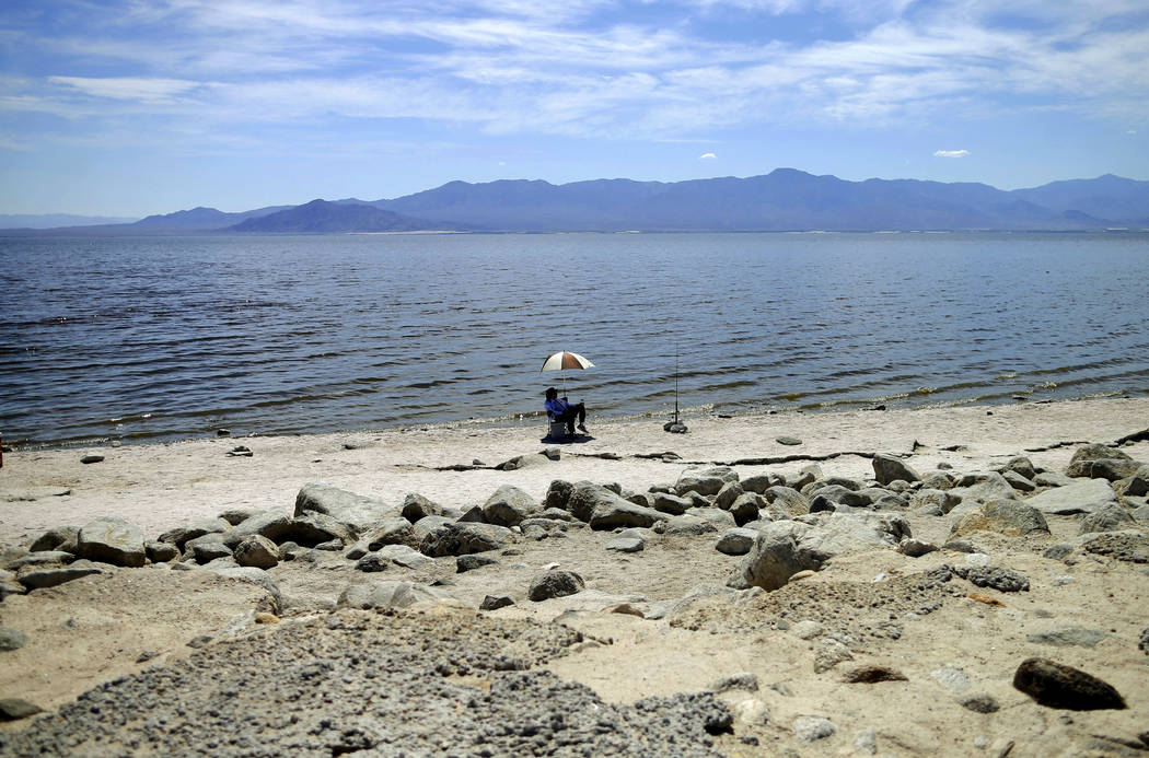 FILE - In this April 30, 2015 file photo, a man fishes for tilapia along the receding banks of the Salton Sea near Bombay Beach, Calif. Work on a multistate plan to address drought on the Colorado ...