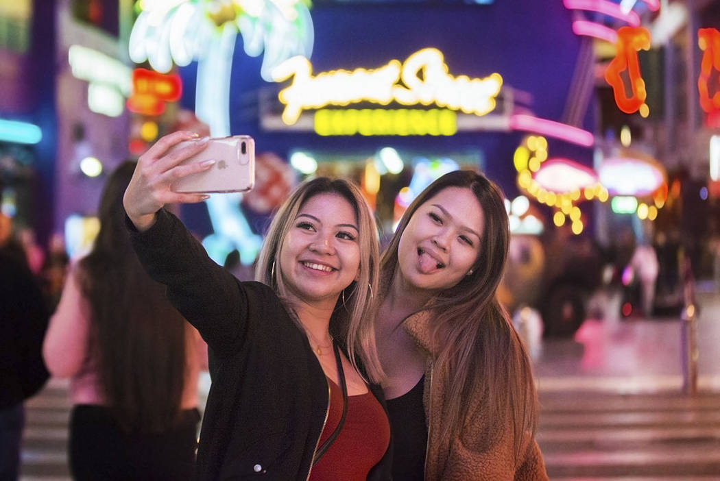 Camile Sangalang, left, and Jasmine Hsiao, both from Vancouver, British Columbia, take a selfie in front of the Fremont Street Experience sign on Wednesday, Jan. 30, 2019, in Las Vegas. (Benjamin ...