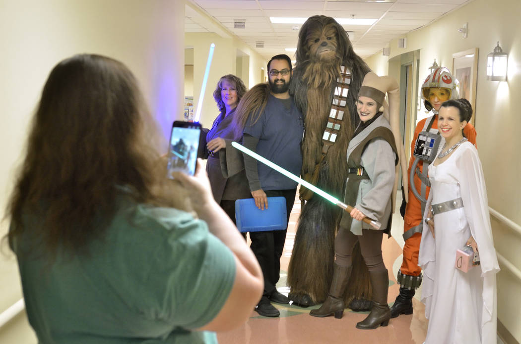 Krystle Hunter, child life specialist at Sunrise Children's Hospital, left, takes a picture of Nehaad Tahsin, a pharmacy technician with Walgreens, third from left, with members of the Rebel Legio ...