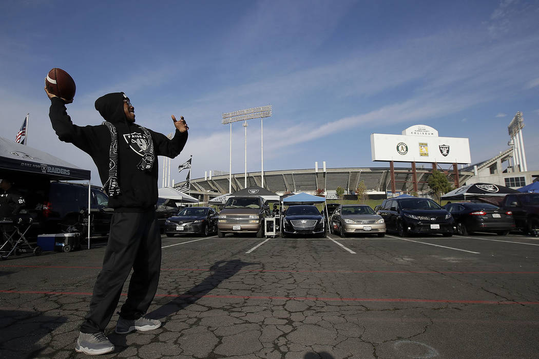 In this Dec. 9, 2018, file photo, a fan throws a football as people tailgate outside Oakland Coliseum before an NFL football game between the Oakland Raiders and the Pittsburgh Steelers in Oakland ...