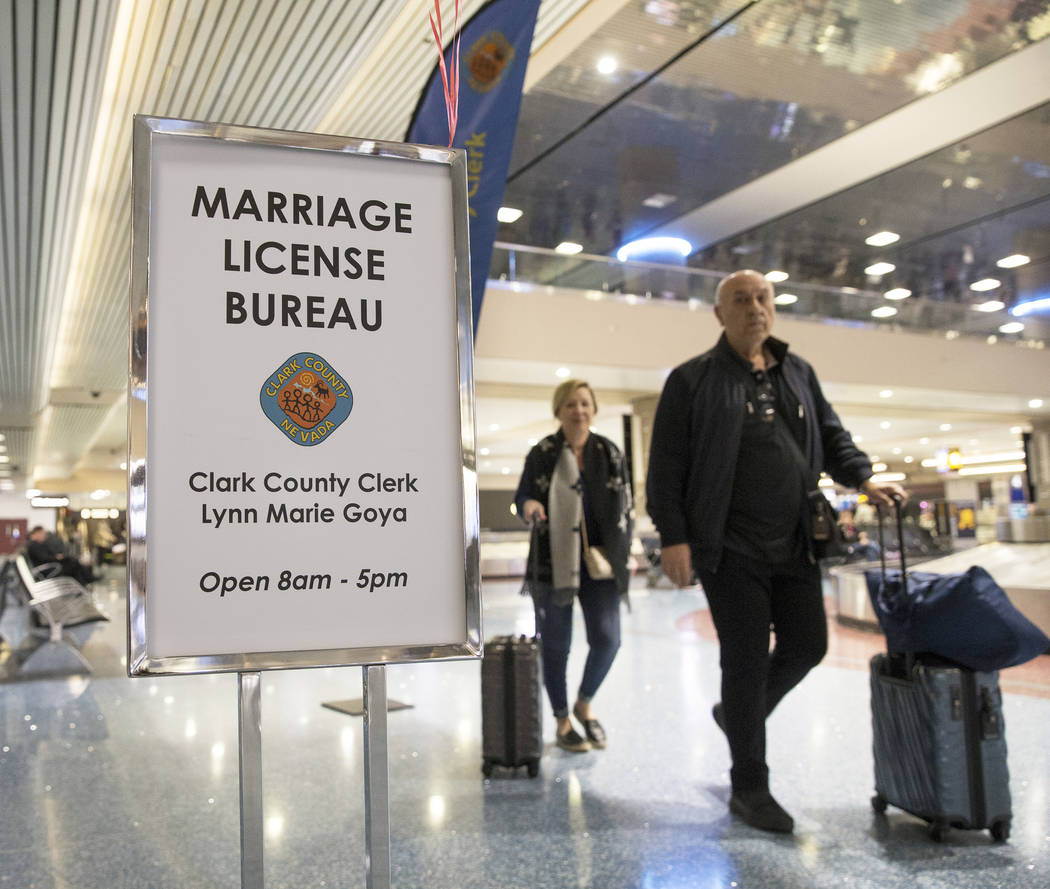 Travelers pass by a Clark County pop-up office offering marriage licenses in the baggage claim area in Terminal 1 on Wednesday, Feb. 13, 2019, at McCarran International Airport, in Las Vegas. (Ben ...