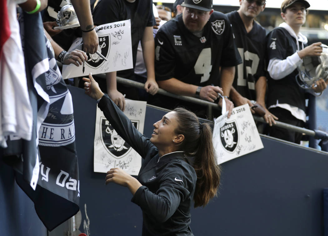 Kelsey Martinez, the Oakland Raiders' strength and conditioning assistant coach, signs autographs before an NFL football preseason game against the Seattle Seahawks, Thursday, Aug. 30, 2018, in Se ...