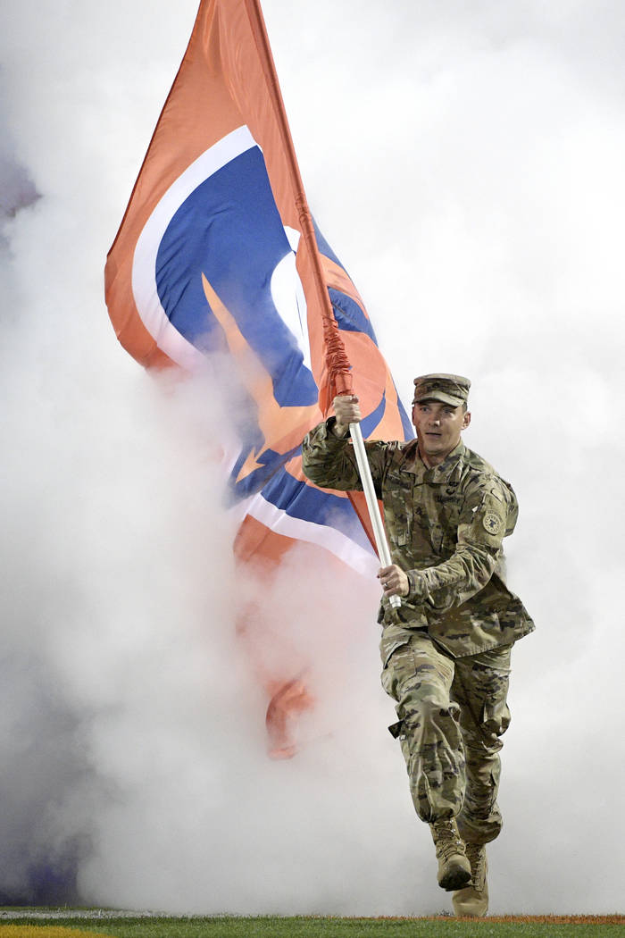 A member of the U.S. military carries a team flag onto the field before an Alliance of American Football game between the Orlando Apollos and the Atlanta Legends on Saturday, Feb. 9, 2019, in Orla ...