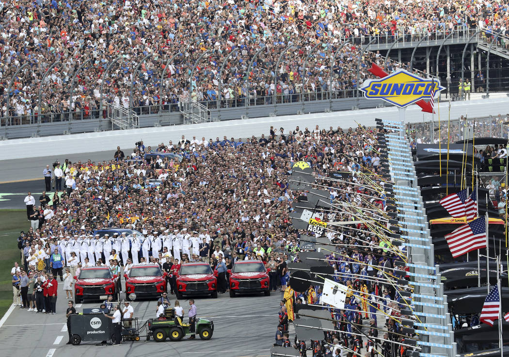 Members of the military, race crews and fans gather on pit road during the national anthem before the start of the NASCAR Daytona 500 auto race at Daytona International Speedway, Sunday, Feb. 17, ...