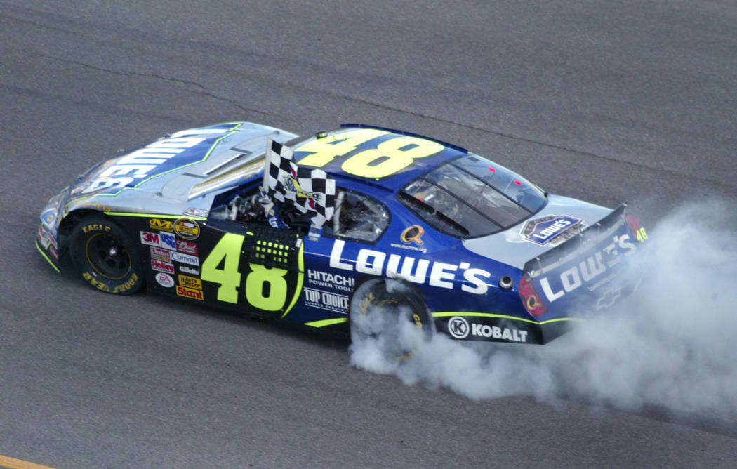 Jimmie Johnson waves the checker flag from his car while doing a burn out after winning the NASCA Nextel Cup UAW-DaimierChrysler 400 at the Las Vegas Motor Speedway Sunday, March 12, 2006. (Jane K ...
