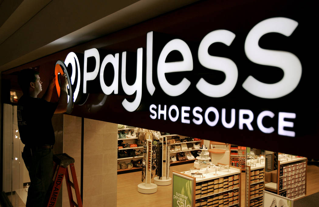 A worker puts the finishing touches on a sign unveiling the company's new look at a Payless Shoesource store at a mall in Independence, Mo. (AP Photo/Charlie Riedel, File)