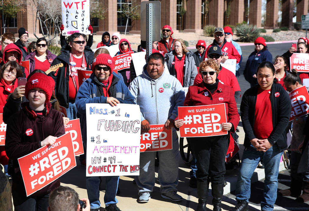 Parents and educators hold signs as they demonstrate their support for the ''Red for Ed'' movement outside of the Grant Sawyer Building on Monday, Feb. 18, 2019, in Las Vegas. Educators dressed in ...