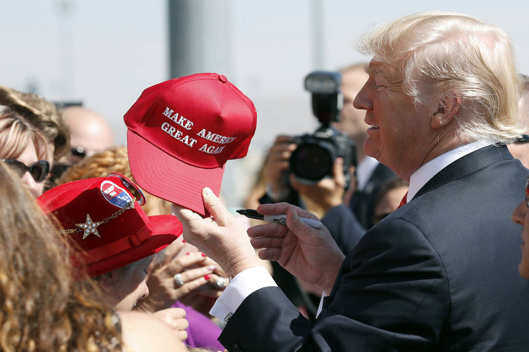 In this Aug. 23, 2017 file photo, President Donald Trump hands a signed "Make America Great Again," hat back to a supporter in Reno, Nev. (AP Photo/Alex Brandon, File)
