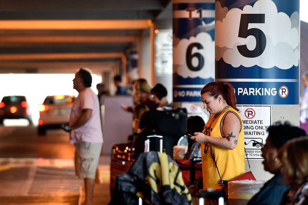 Genevieve Kocak of Las Vegas checks her mobile device as she waits for her ride in the passenger pick-up area at McCarran International Airport Monday, March 14, 2016, in Las Vegas. (David Becker ...