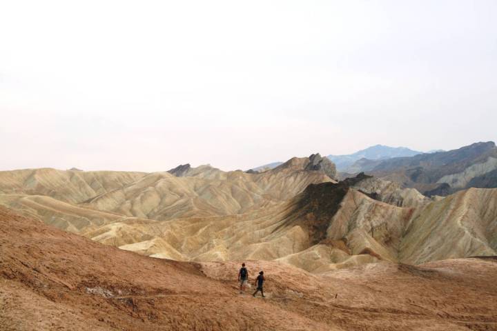 Hikers head across the badlands below Zabriskie Point in Death Valley National Park, California ...