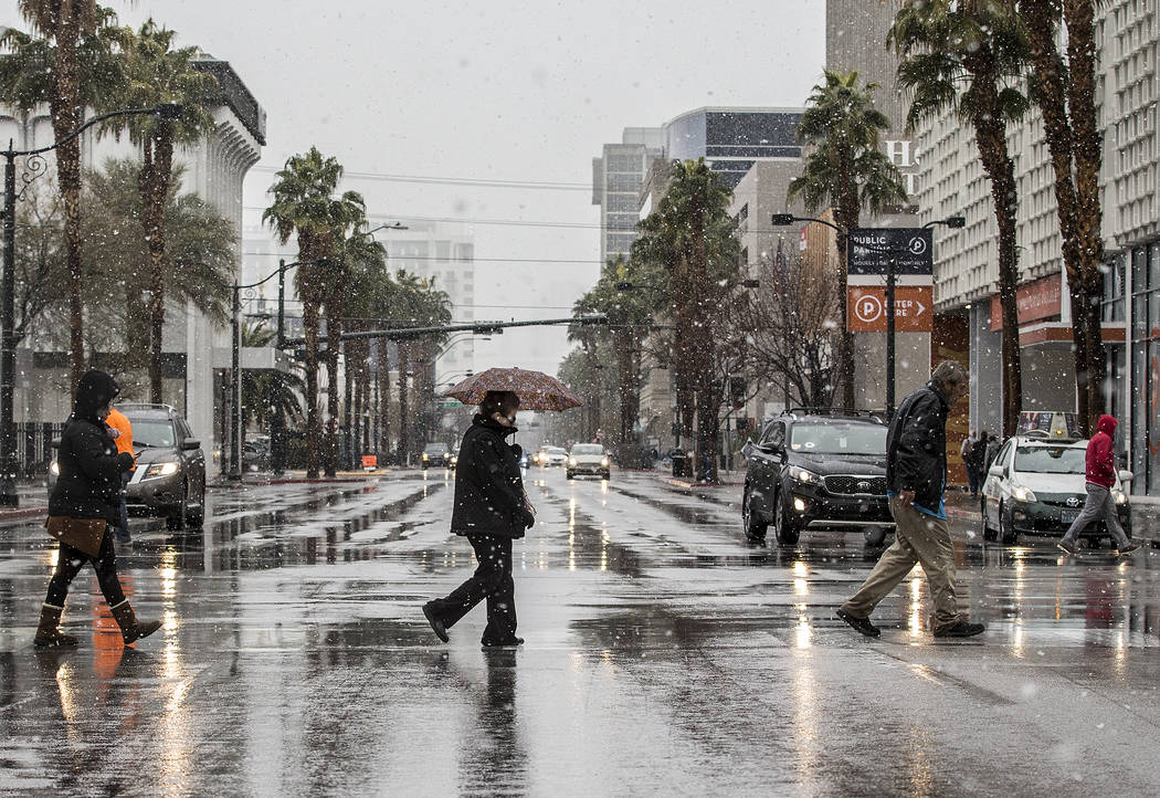 Pedestrians try to stay warm and dry in the early morning snow in Downtown Las Vegas on Thursday, Feb. 21, 2019. (Benjamin Hager Review-Journal) @BenjaminHphoto