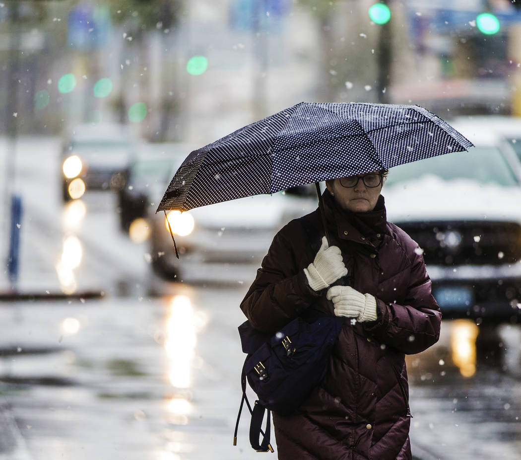 Pedestrians try to stay warm and dry in the early morning snow in Downtown Las Vegas on Thursday, Feb. 21, 2019. (Benjamin Hager Review-Journal) @BenjaminHphoto