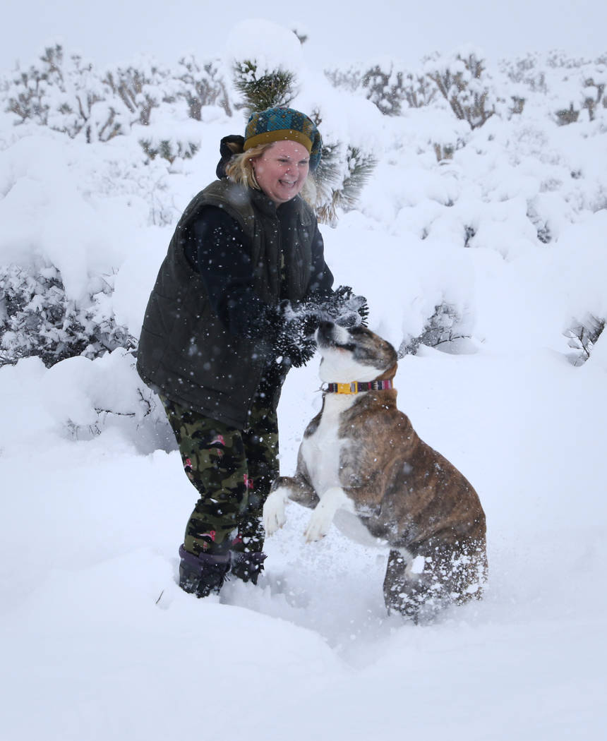 Kristi Collins of Heart Butte, Montana, plays with her dog Jax as snow falls along state Route 159 near Bonnie Springs Ranch around the Red Rock Canyon National Conservation Area outside Las Vegas ...