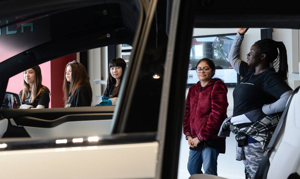 Middle school students peer into one of the Tesla cars on display as Tesla celebrates "Introduce a Girl to Engineering Day" at its Sahara showroom in Las Vegas, Thursday, Feb. 21, 2019. (Caroline ...