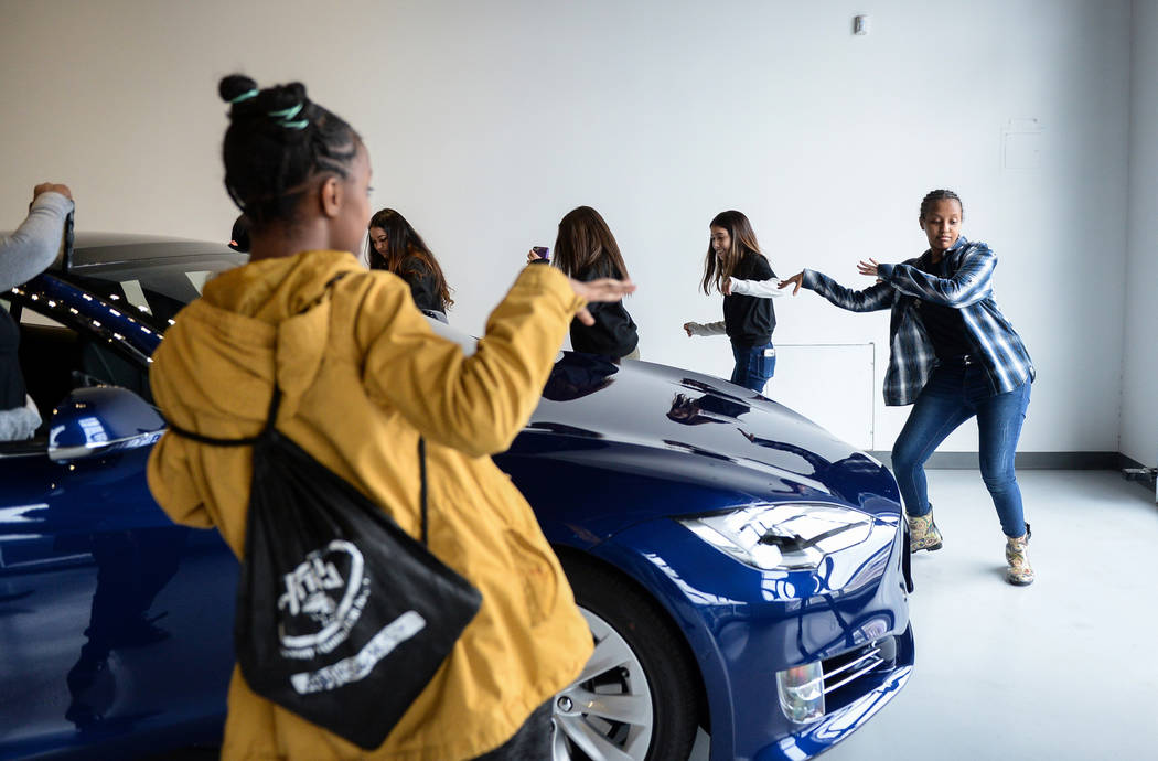 Middle school students dance to music they put on in one of the Tesla cars on display as Tesla celebrates "Introduce a Girl to Engineering Day" at its Sahara showroom in Las Vegas, Thursday, Feb. ...