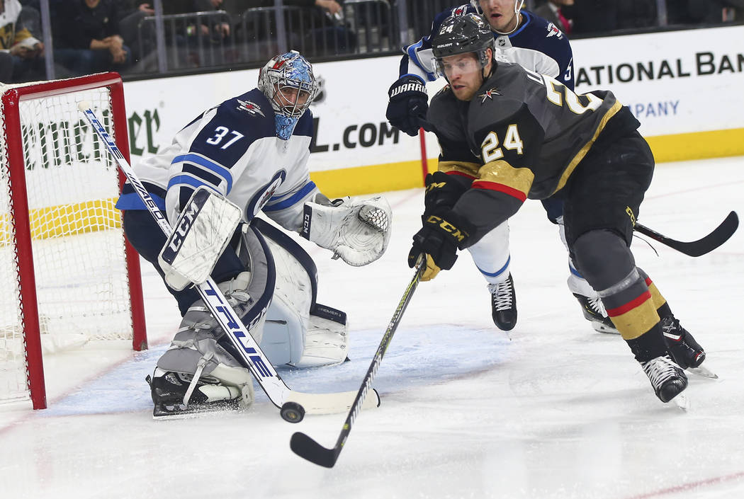 Golden Knights center Oscar Lindberg (24) tries to get the puck in past Winnipeg Jets goaltender Connor Hellebuyck (37) during the second period of an NHL hockey game at T-Mobile Arena in Las Vega ...