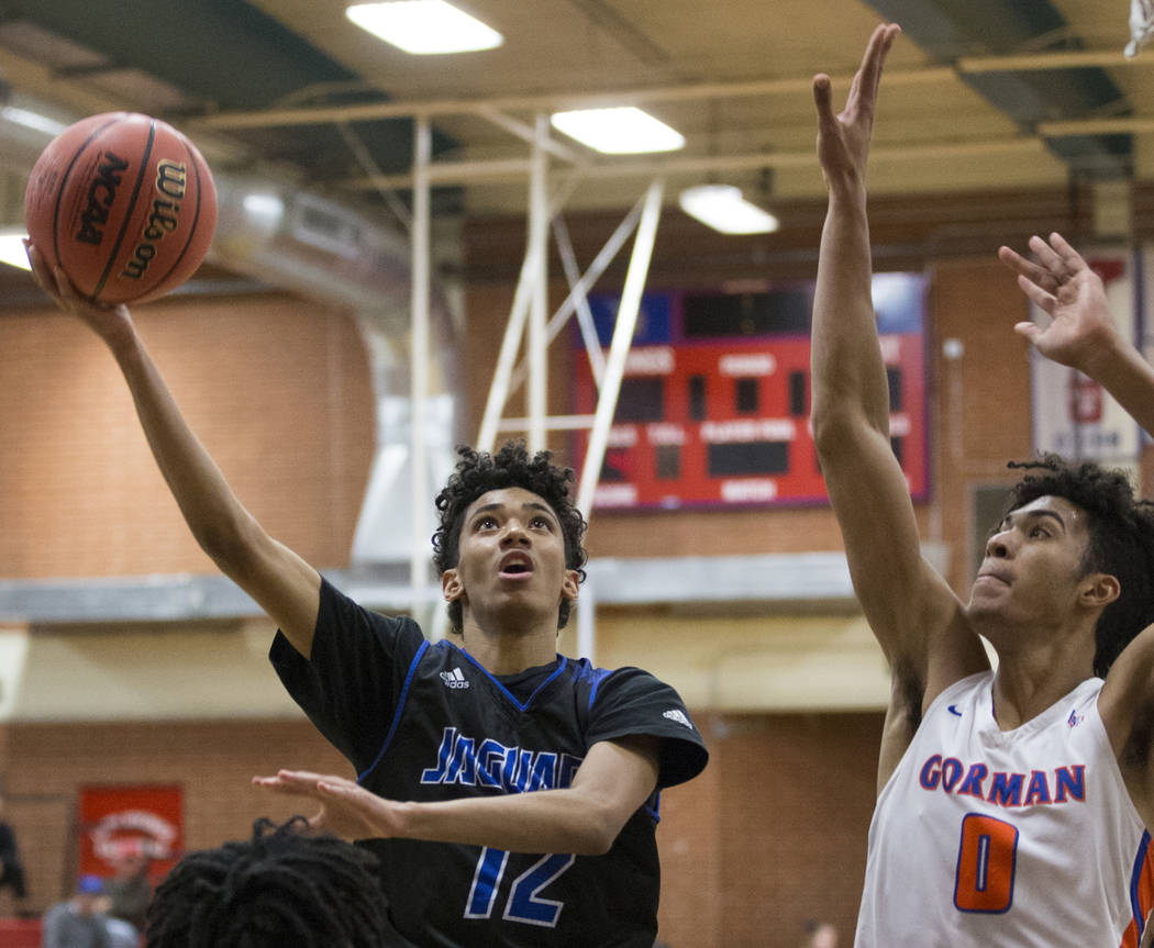 Desert Pines freshman Milos Uzan (12) splits Bishop Gorman junior forward Isaiah Cottrell (0) and sophomore guard Will McClendon (1) in the third quarter during the Southern Nevada boys basketball ...