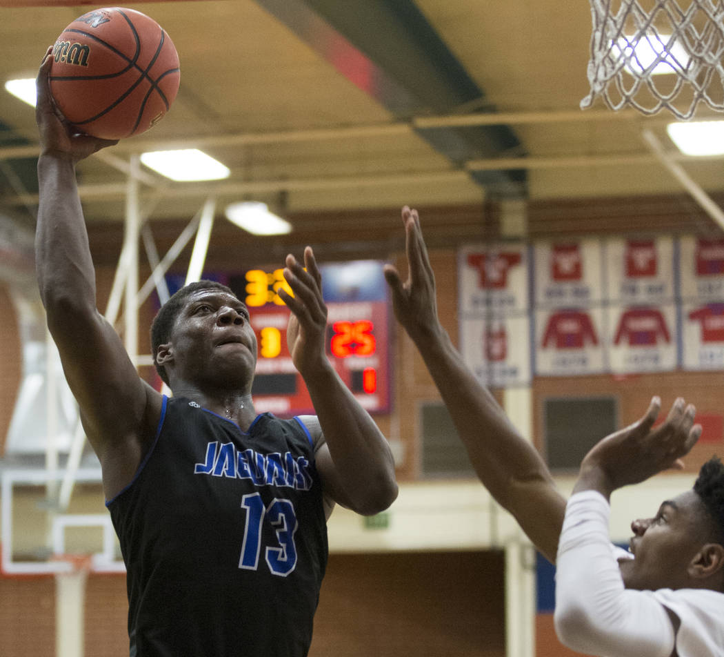 Desert Pines junior Darnell Washington (13) drives to the rim over Bishop Gorman sophomore guard Zaon Collins (10) in the fourth quarter during the Southern Nevada boys basketball championship gam ...