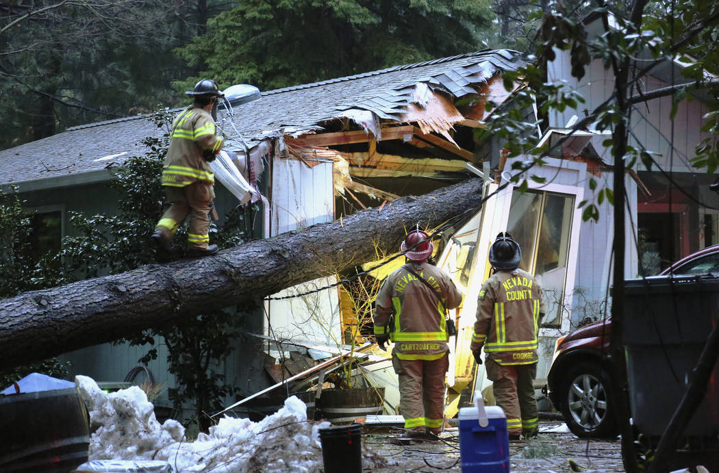 Nevada County and Nevada City firefighters work to assess a structure on Juniper Drive that sustained a tree fall, knocking out power and potentially causing a gas hazard in the process, Tuesday e ...
