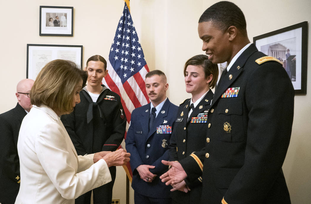 In this Tuesday, Feb. 5, 2019 photo released by the her office, Speaker of the House Nancy Pelosi, D-Calif., left, gives challenge coins to U.S. Army Maj. Ian Brown, right, and other military serv ...