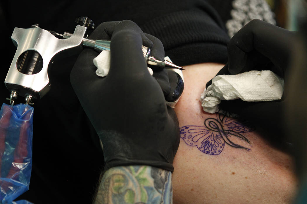 Seth Moore, tattoo artist at Diversity Tattoo shop, tattoos the arm of Carrie Johnson, at Diversity Tattoo in Las Vegas Saturday, Oct. 4, 2014. (Erik Verduzco/Las Vegas Review-Journal)