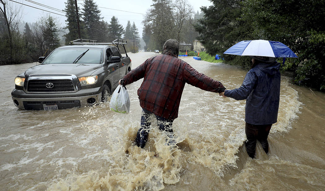 Residents along Armstrong Woods Road head back to their home after the road became impassable to most vehicles, Tuesday, Feb. 26, 2019 in Guerneville, Calif. (Kent Porter/The Press Democrat via AP)