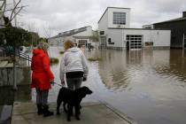 Two women and a dog look out at the flooded Barlow Market District, Wednesday, Feb. 27, 2019, in Sebastopol, Calif. (Eric Risberg/AP)