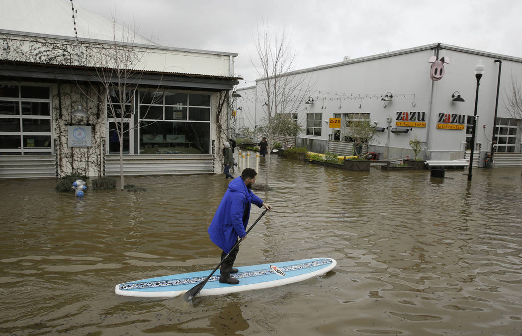 A man uses a paddle board to make his way through the flooded Barlow Market District Wednesday, Feb. 27, 2019, in Sebastopol, Calif. (Eric Risberg/AP)