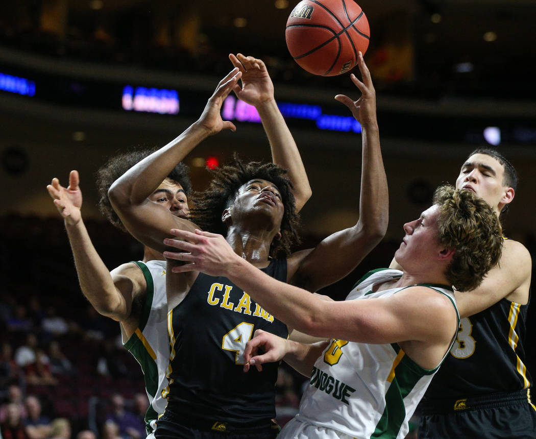 Clark's Carlos Allen (4) reaches up for the ball while being guarded by Bishop Manogue's Curtis Luckadoo (4) and Brayden Debruin (0) during the first half of a Class 4A state boys basketball semif ...