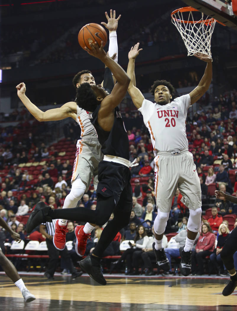 San Diego State Aztecs guard Devin Watson goes to the basket under pressure from UNLV Rebels guard Noah Robotham, left, and forward Nick Blair (20) during the first half of a basketball game at th ...
