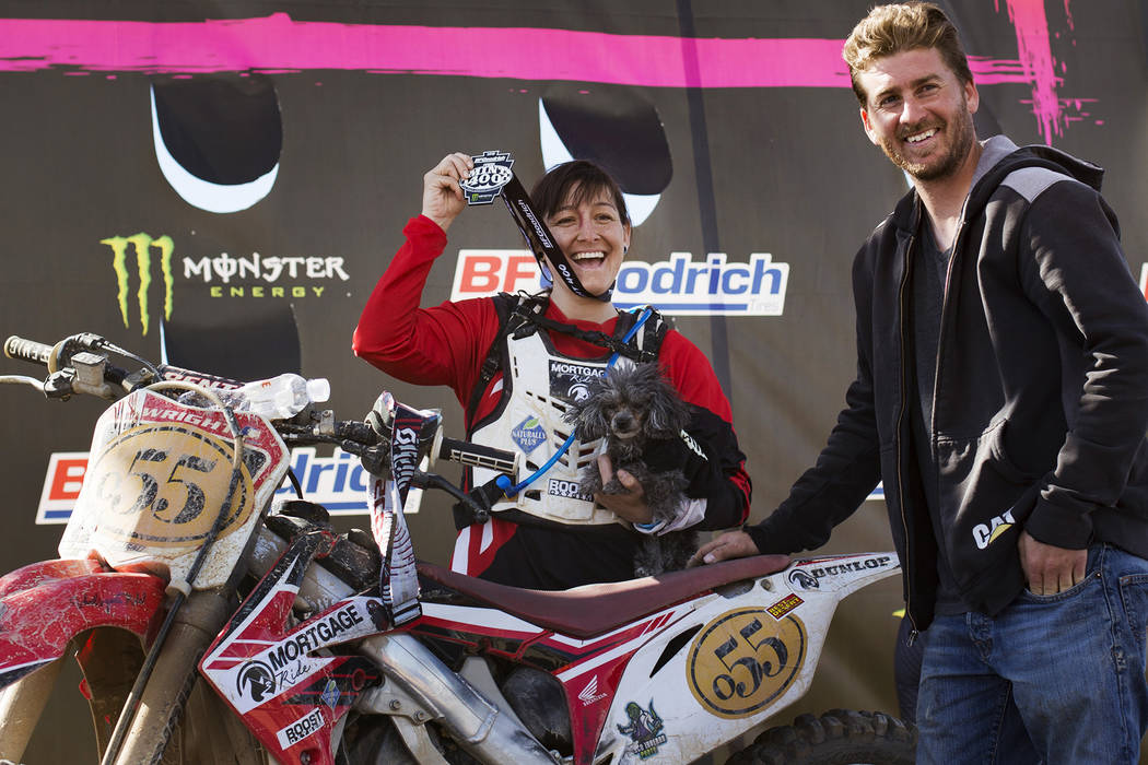 Angie Wright holds her medal next to her boyfriend Derek Stephens and her dog Phoenix after completing the Mint 400 motorcycle race in Primm, Nevada, Saturday, March 9, 2019. She completed in the ...