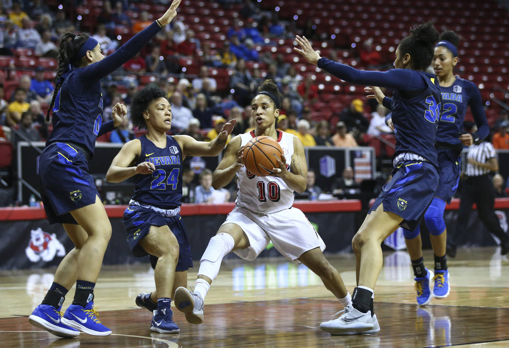 UNLV Lady Rebels guard Nikki Wheatley (10) drives between UNR Wolf Pack guards Camariah King (24) and Jade Redmon, right, during the second half of a basketball game in the Mountain West tournamen ...