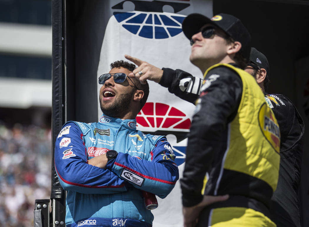 Bubba Wallace, left, watches the United States Air Force Thunderbirds make a pass above Las Vegas Motor Speedway before the start of the Monster Energy NASCAR Cup Series Pennzoil 400 on Sunday, Ma ...