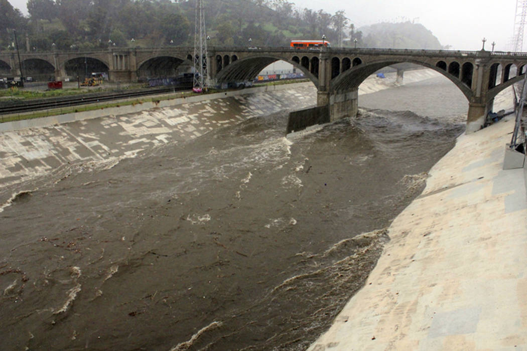 In this Feb. 2, 2019 file photo, water races down the concrete-lined channel of the swollen Los Angeles River, under the North Broadway Bridge near downtown Los Angeles, as a powerful storm drench ...
